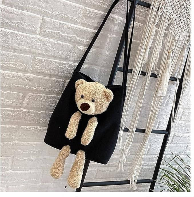 Black cute shoulder bag with plush teddy bear hanging on a ladder against a white brick wall background