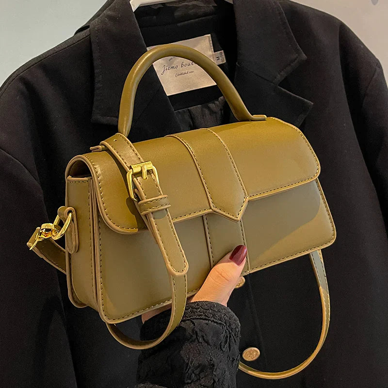 Stylish olive green women bag with adjustable strap and top handle on black coat background
