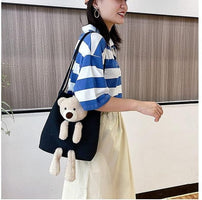 Woman carrying a black cute shoulder bag tote with a plush teddy bear attached