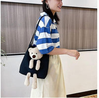 Woman carrying a black cute shoulder bag tote with a plush teddy bear attached
