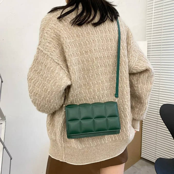 Green leather women shoulder bag with adjustable strap worn crossbody with beige sweater and brown skirt