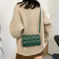 Green leather women shoulder bag with adjustable strap worn crossbody with beige sweater and brown skirt