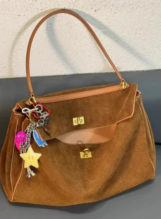 Brown leather crossbody bag for women with gold clasp and decorative keychain charms
