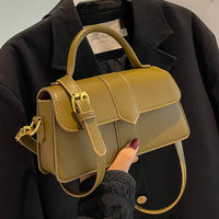 Stylish olive green women bag with adjustable strap and top handle on black coat background