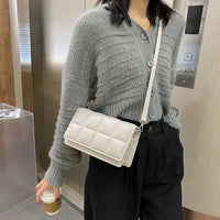 woman wearing grey sweater with white leather compact women shoulder bag carrying coffee cup indoors