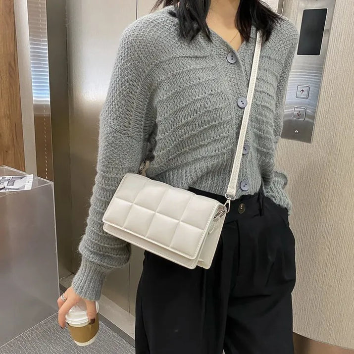 woman wearing grey sweater with white leather compact women shoulder bag carrying coffee cup indoors